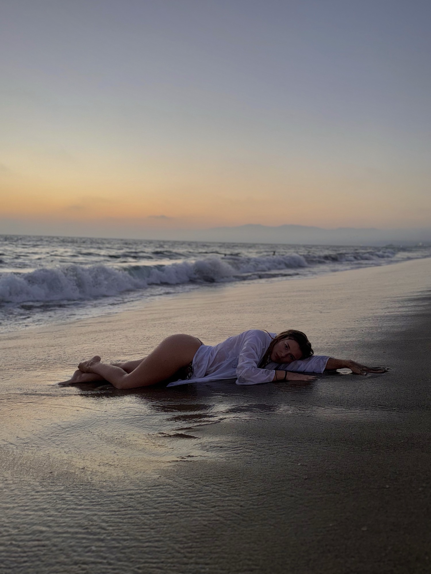 Melinda lying on the beach at sunset