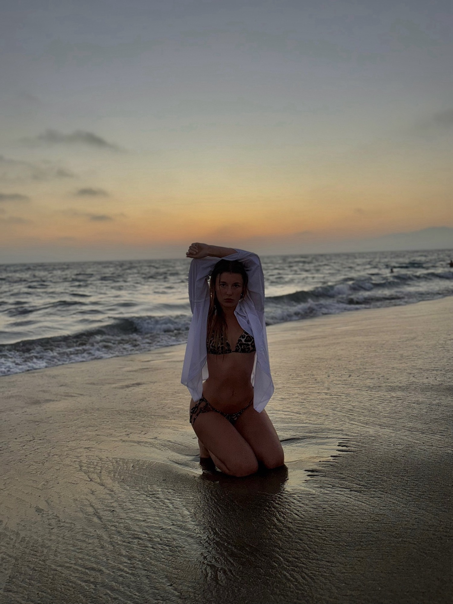 Melinda kneeling at the shore at sunset