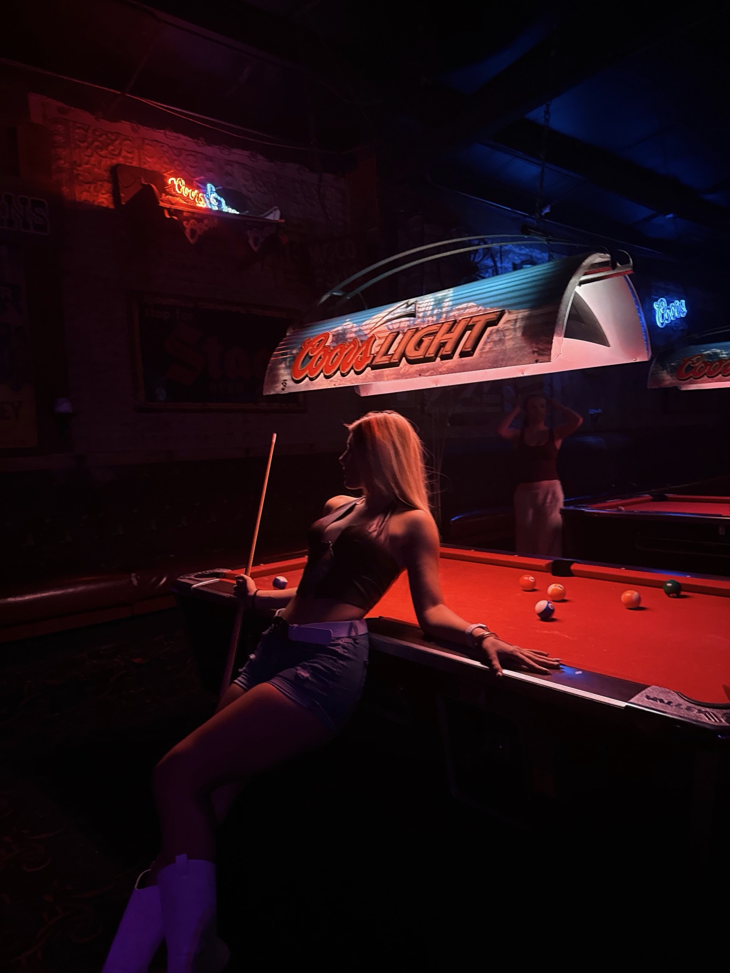 At the pool table under Coors Light neon